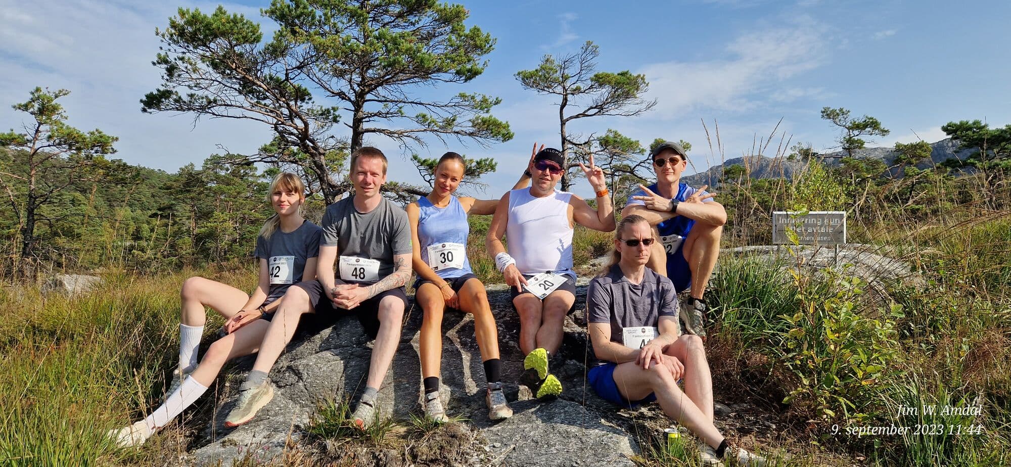 Deltakere i Prosjekt SUT med startnummer sitter sammen på en stein i sola